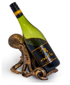 A green wine bottle with a black and gold Arabila label, displayed in a decorative bronze-colored octopus-shaped holder against a plain white background.