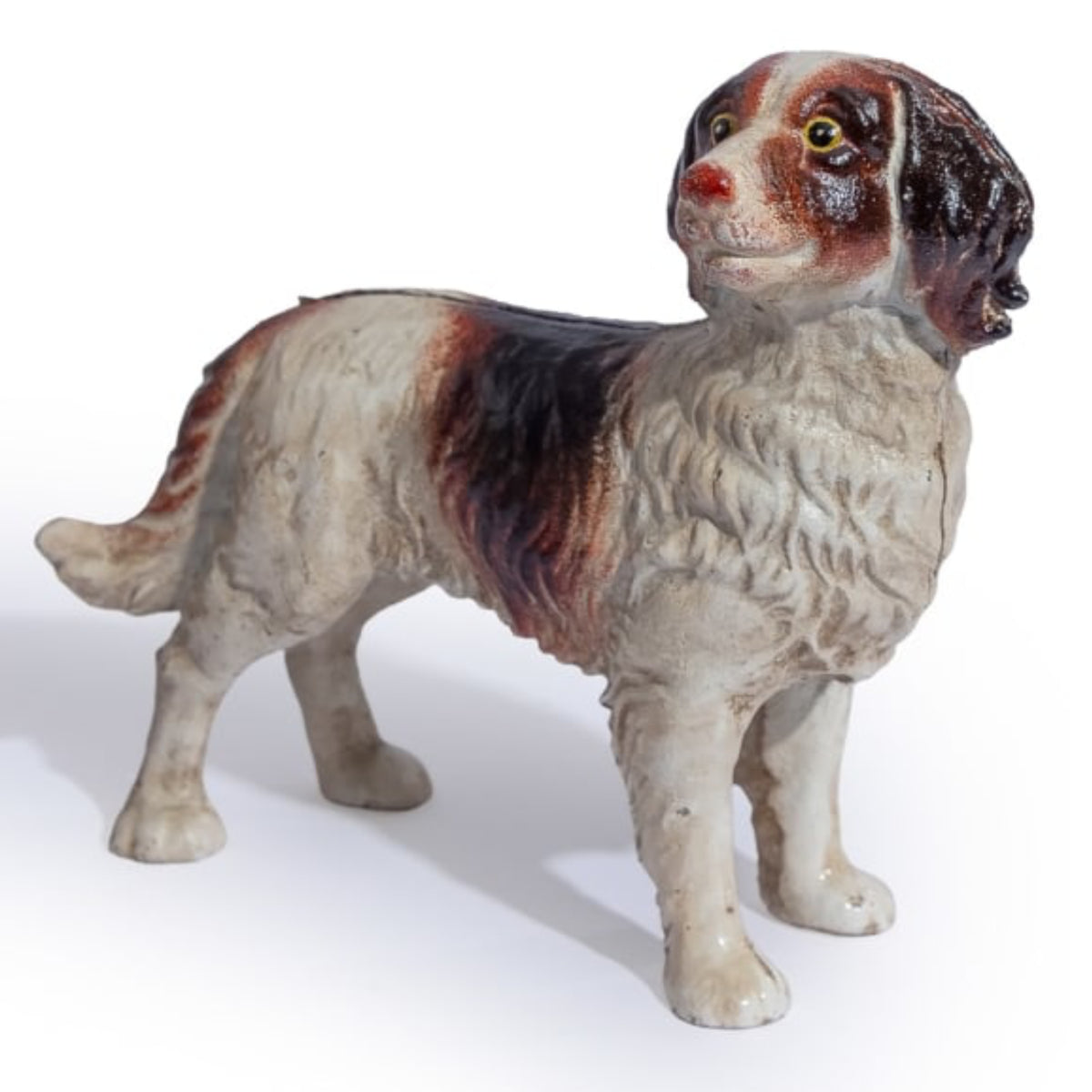 A vintage ceramic dog figurine, likely a spaniel or retriever, featuring a glossy glaze with cream, brown, and black coloring. The figurine is posed standing and photographed against a clean white background.