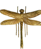 Gold dragonfly sculpture on a light gray background