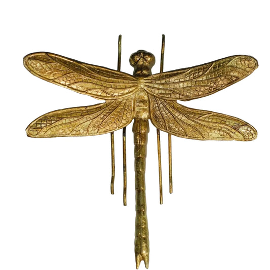 Gold dragonfly sculpture on a light gray background
