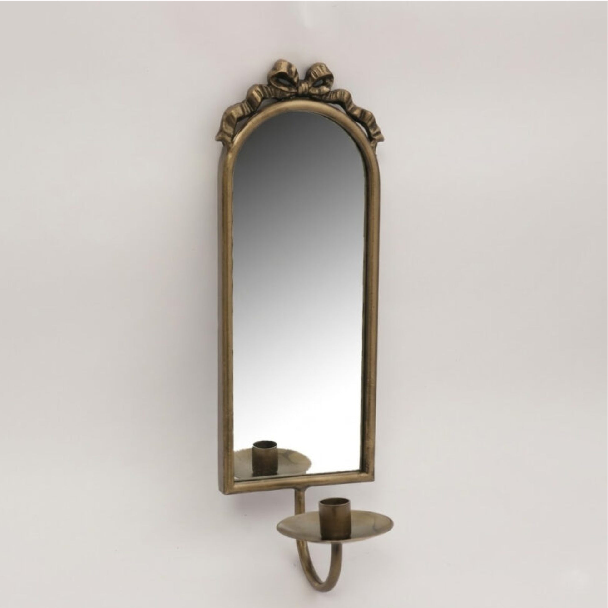 An antique-style wall sconce featuring an arched mirror with an ornate bronze frame and a matching candle holder below, mounted against a plain light gray wall.