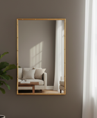 Rectangular mirror with gold frame on a wall, reflecting a living room.
