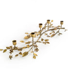 Decorative gold candle holder shaped like a leafy branch on a white background