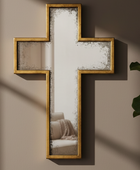 Decorative cross-shaped mirror on a wall with a plant to the right