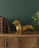 Gold dog statue on a wooden shelf with books and a plant against a green wall