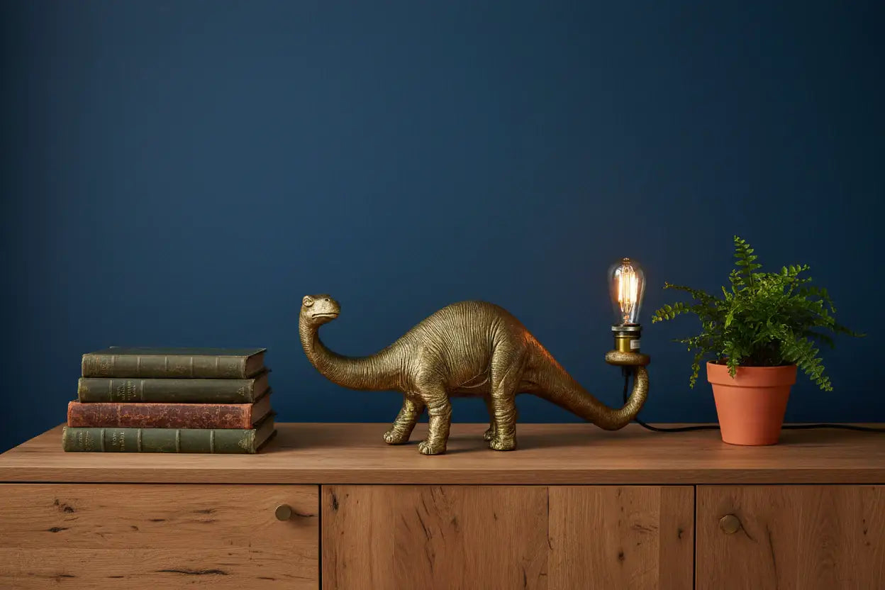 Dinosaur lamp on a wooden surface with books and a plant against a blue wall