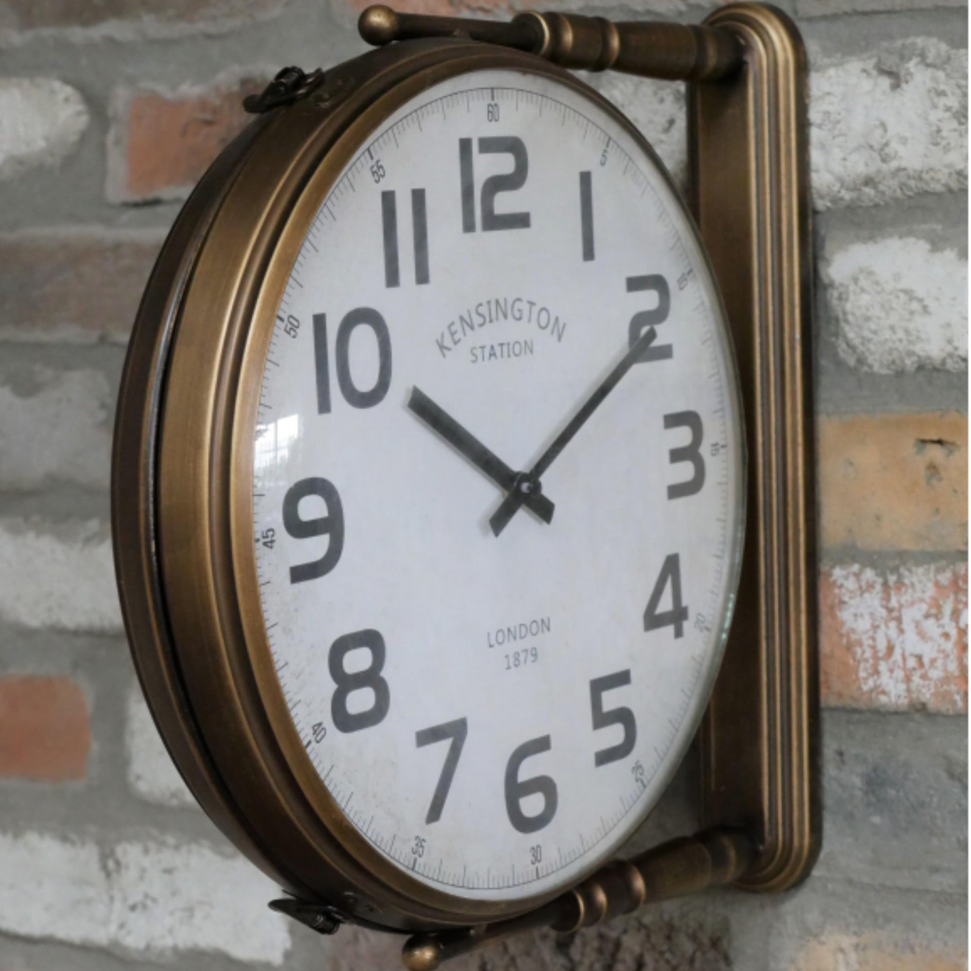 Vintage-style wall clock with brass frame on a brick wall.