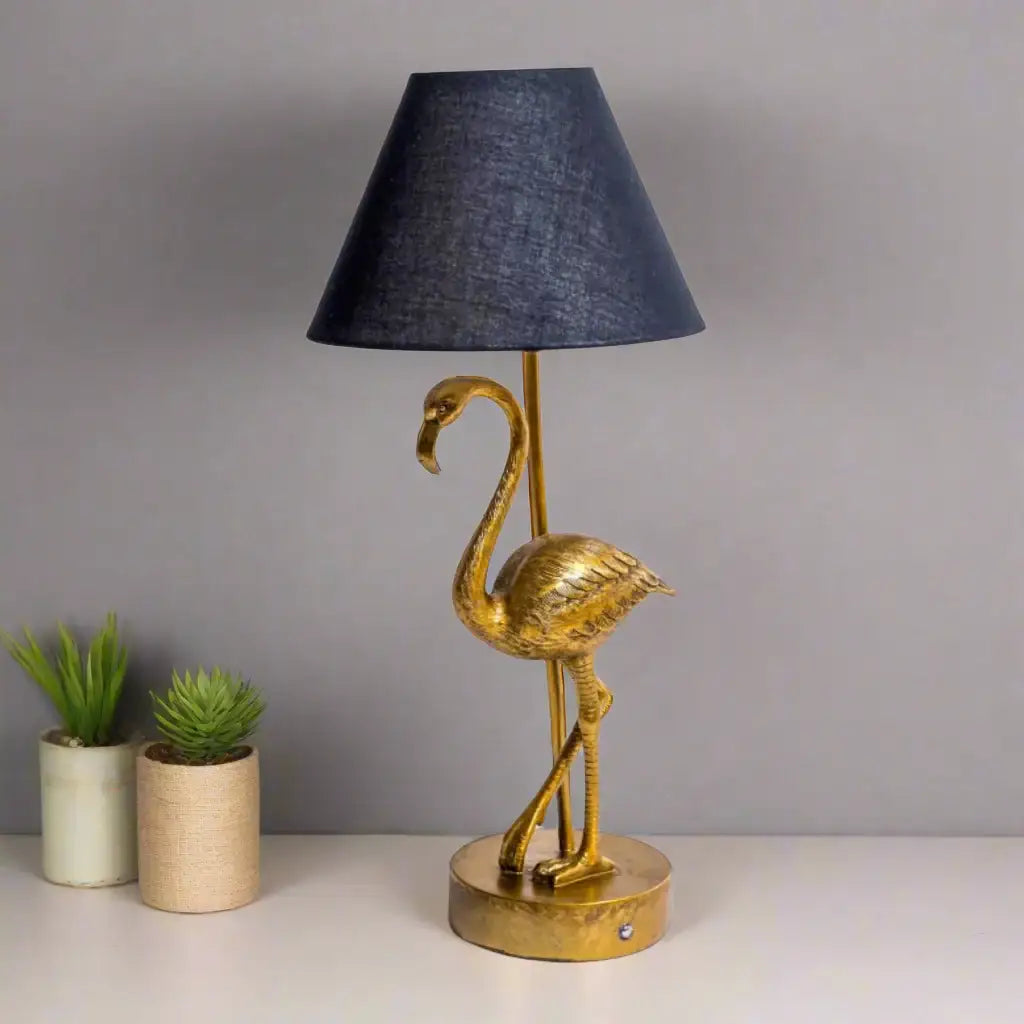 Gold flamingo table lamp with a black lampshade on a white background