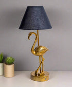 Gold flamingo table lamp with a black lampshade on a white background