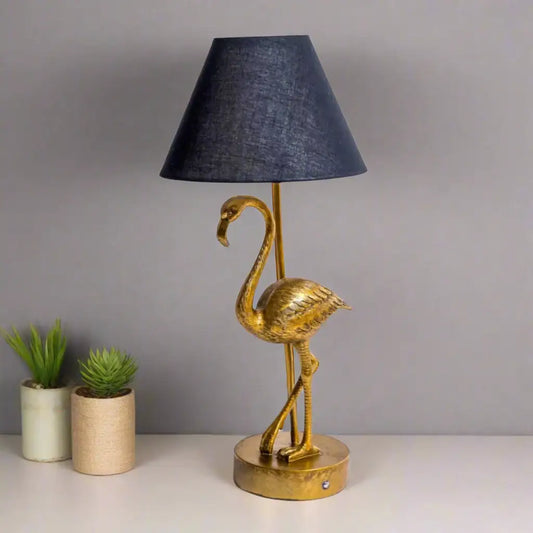 Gold flamingo table lamp with a black lampshade on a white background