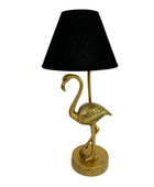 Gold flamingo-shaped table lamp with a black lampshade on a white background