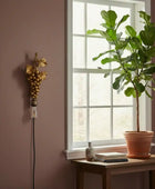 Potted plant on a windowsill with decorative light fixture on the wall.