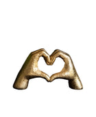 Bronze sculpture of two hands forming a heart shape on a white background