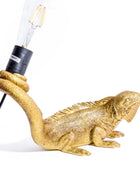 Gold iguana-shaped lamp with a light bulb on a white background