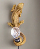Gold lizard-shaped wall light fixture on a white background