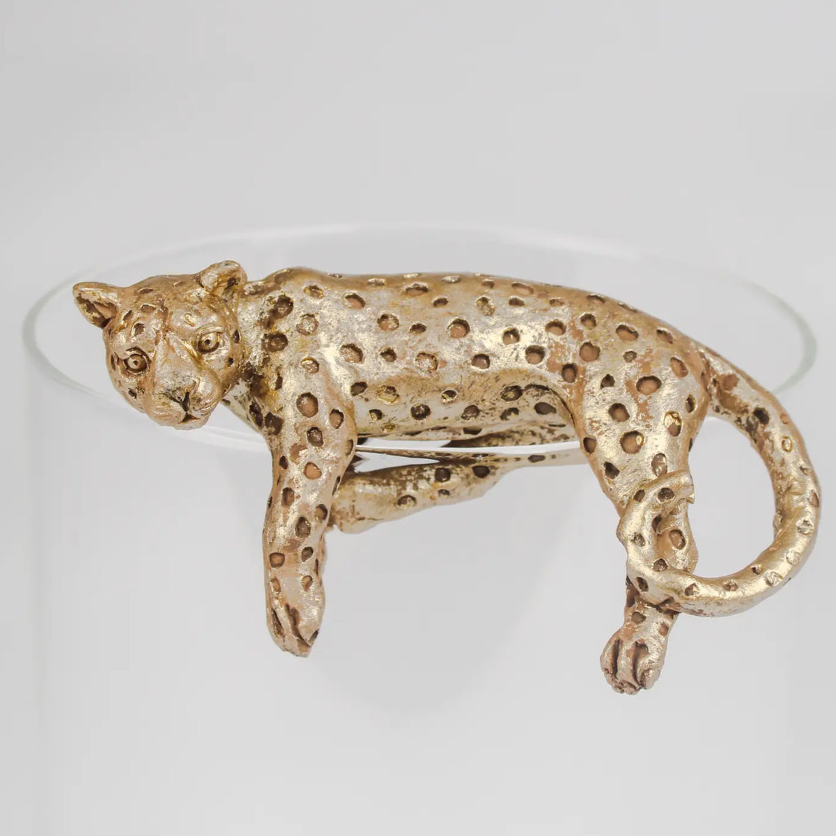 A leopard-shaped brooch in textured gold-tone metal with a spotted pattern, shown on a plain light gray background.