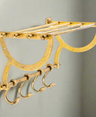 Gold wall-mounted hook rack with multiple hooks on a white background