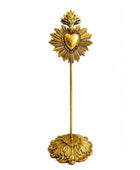 A gold Sacred Heart of Jesus tabletop candle holder featuring an ornate base, a slender stem, and a decorative top with a radiant halo and central heart, shown on a plain white background.