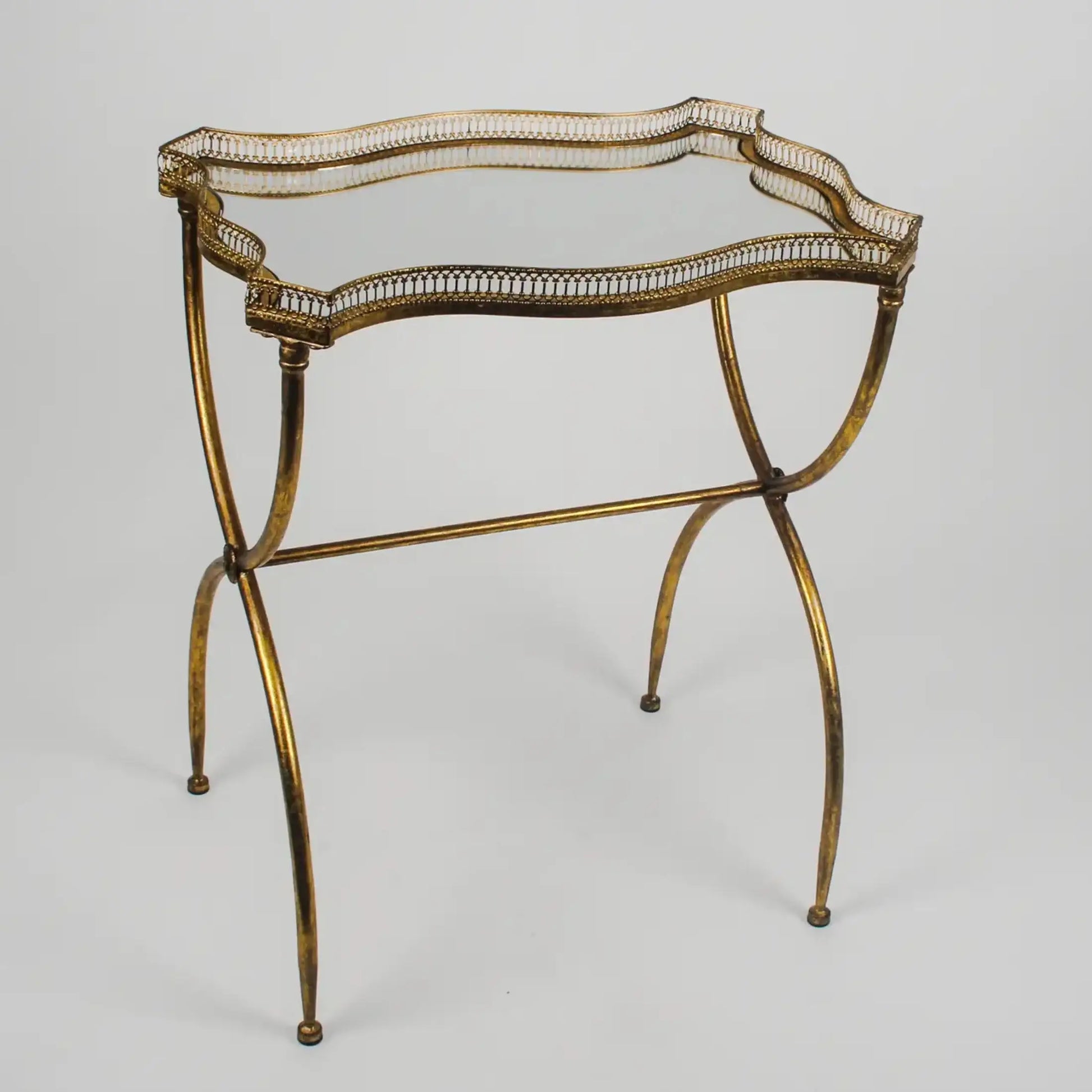 Decorative gold metal table with intricate design on a gray background
