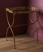 Gold metal side table against a pink wall