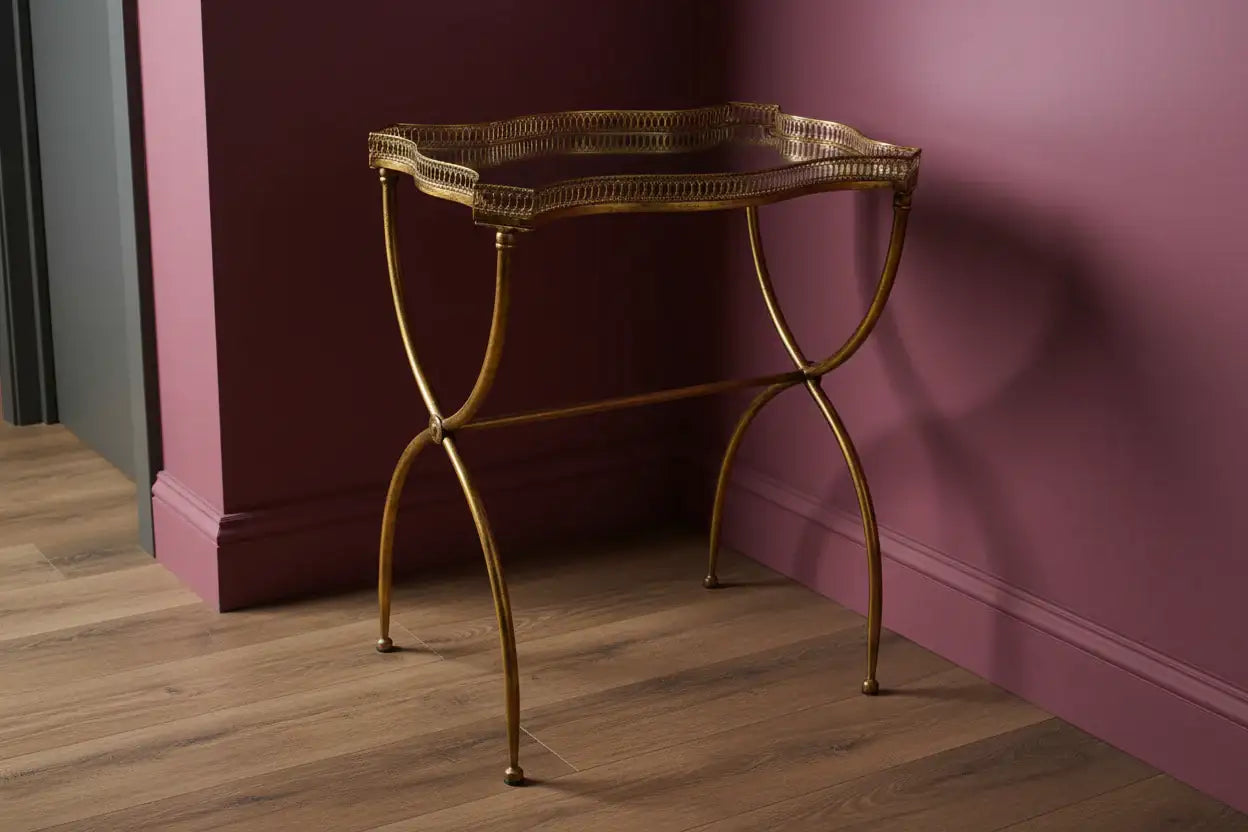 Gold metal side table against a pink wall