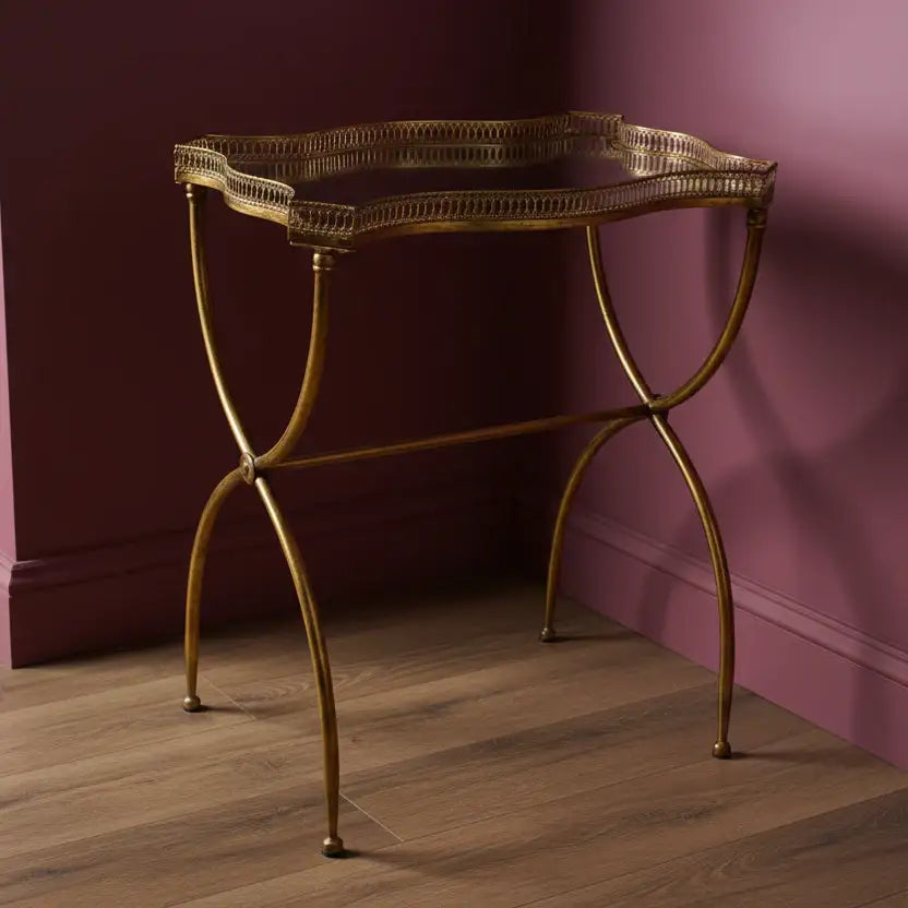 Gold metal console table against a purple wall