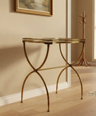 Gold metal side table in a room with a coat rack and painting on the wall.