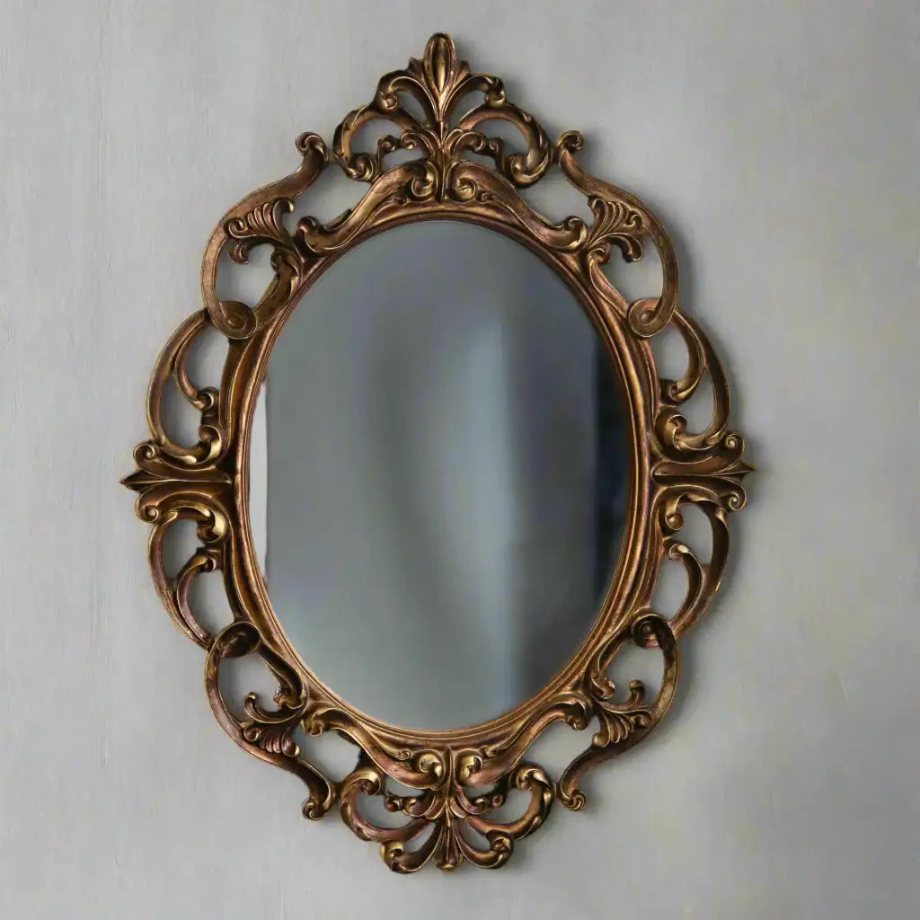 Decorative oval mirror with intricate gold frame on a light gray wall
