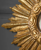 Close-up of a gold decorative mirror with intricate designs on a dark background