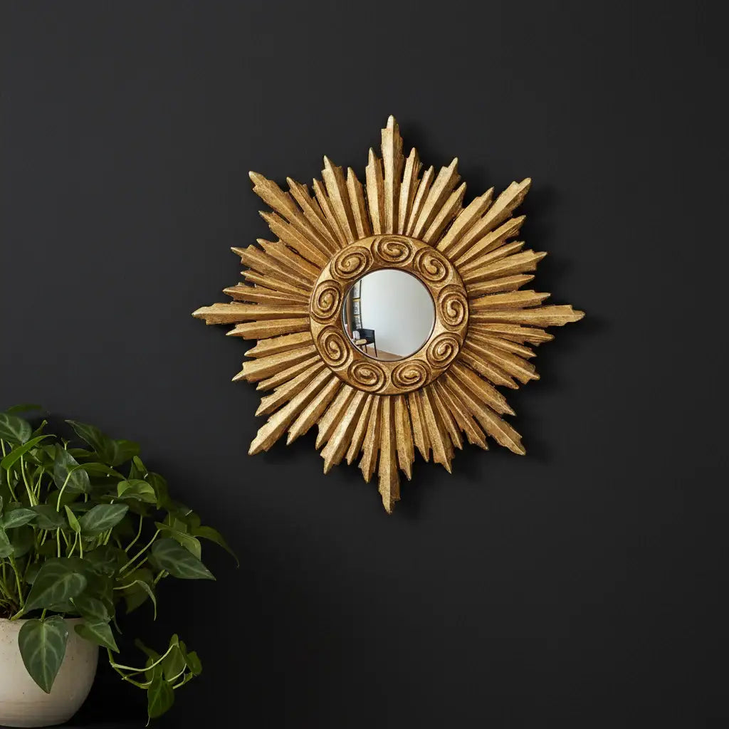 Decorative sunburst mirror on a black wall with a plant to the left.