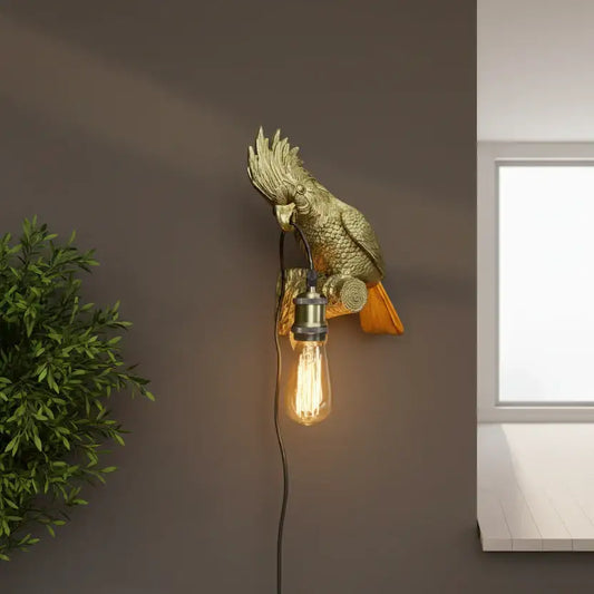 Gold parrot-shaped wall light fixture with a lit bulb on a brown wall.