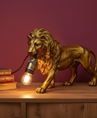 Gold lion statue with a light bulb as a lamp on a wooden surface against a purple wall.