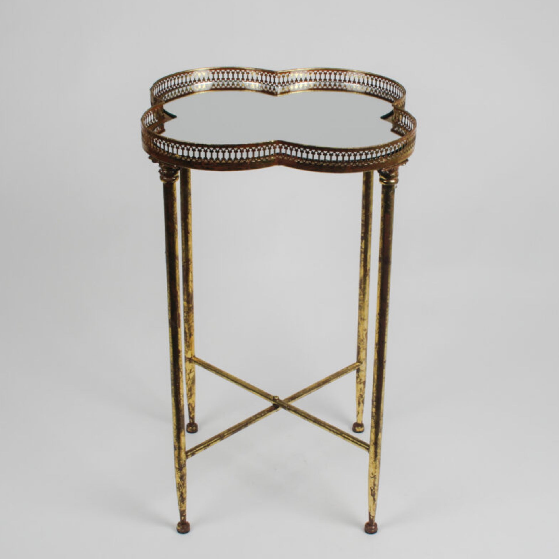 Decorative side table with gold metal frame and glass top on a gray background