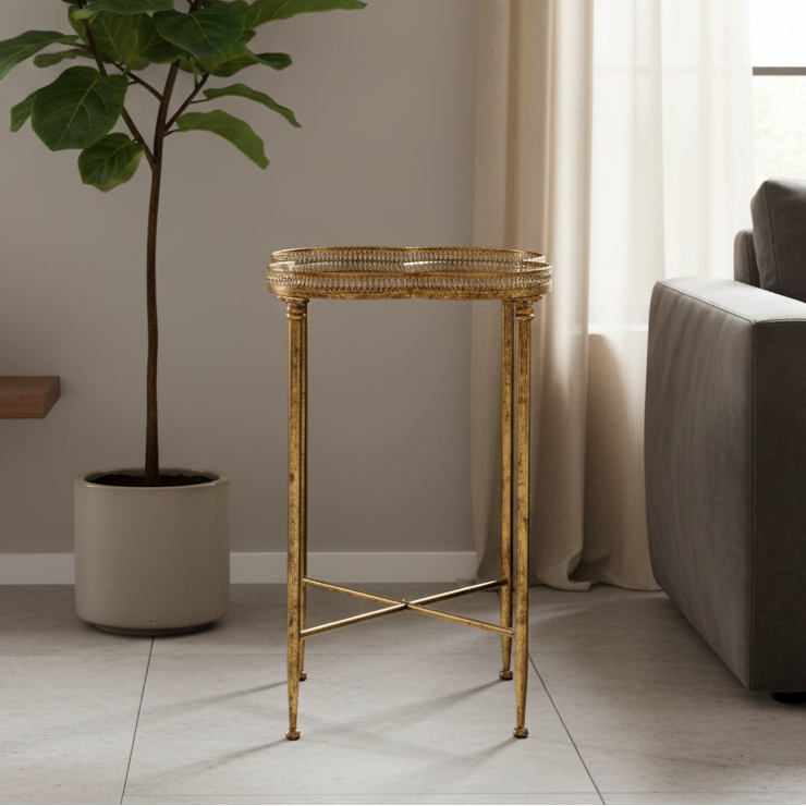 Gold side table in a living room setting with a plant and sofa.