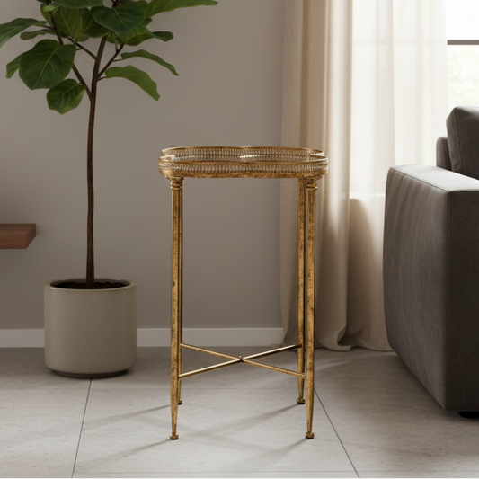 Gold side table in a living room setting with a plant and sofa.
