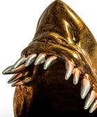 Bronze sculpture of a creature with sharp teeth on a white background