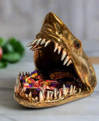 Bronze shark-shaped candy dish with open mouth displaying colorful candies on a marble surface.