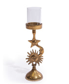 A decorative brass candle holder with a clear glass candle sleeve, featuring celestial sun and moon faces on a white background.
