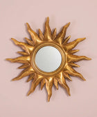 Gold sun-shaped mirror on a pink background