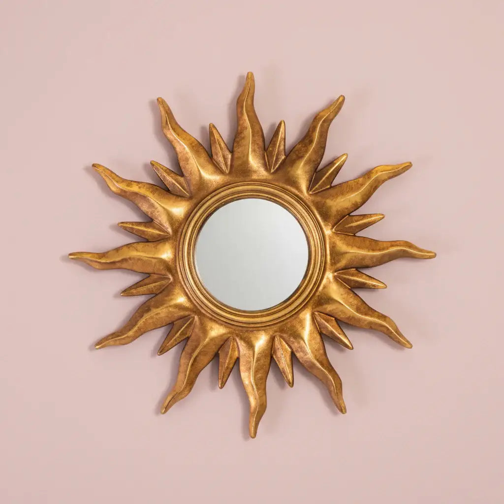 Gold sun-shaped mirror on a pink background