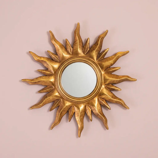 Gold sun-shaped mirror on a pink background