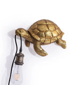 Gold turtle-shaped wall lamp with a bulb on a white background