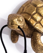 Bronze turtle sculpture with a black cord on a white background