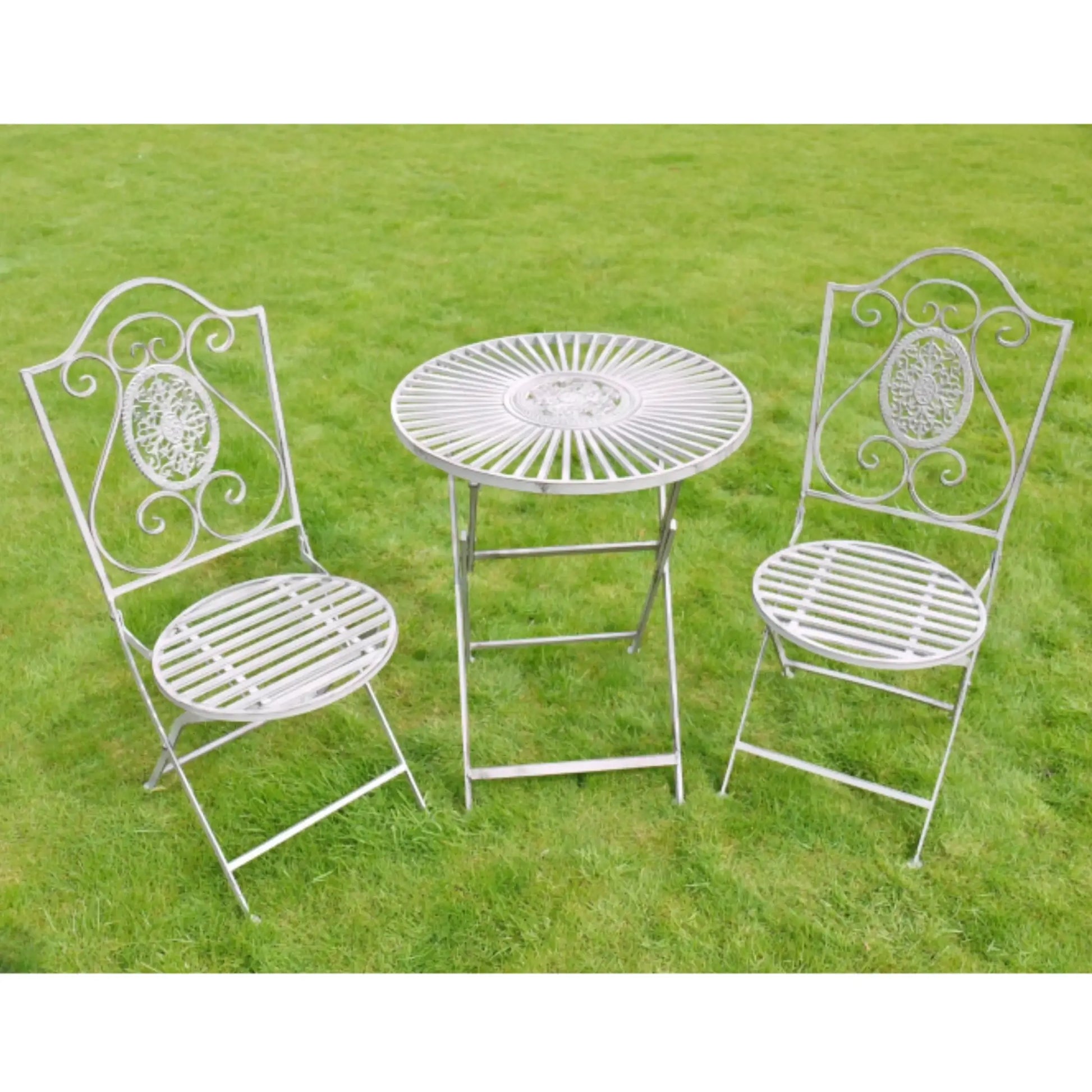 White metal garden table and chairs on a grassy background