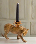 Gold panther candle holder with a black candle on a neutral background