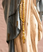 Gold rosary hanging on a wooden surface with a blurred background