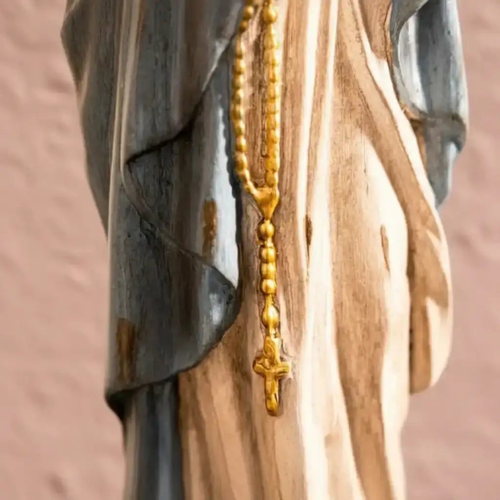 Gold rosary hanging on a wooden surface with a blurred background