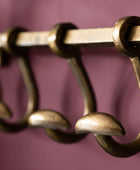 Close-up of a set of brass hooks on a purple background