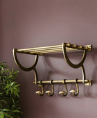 Brass towel rack with hooks on a purple wall