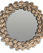 Round mirror with leaf-like gold frame on a white background
